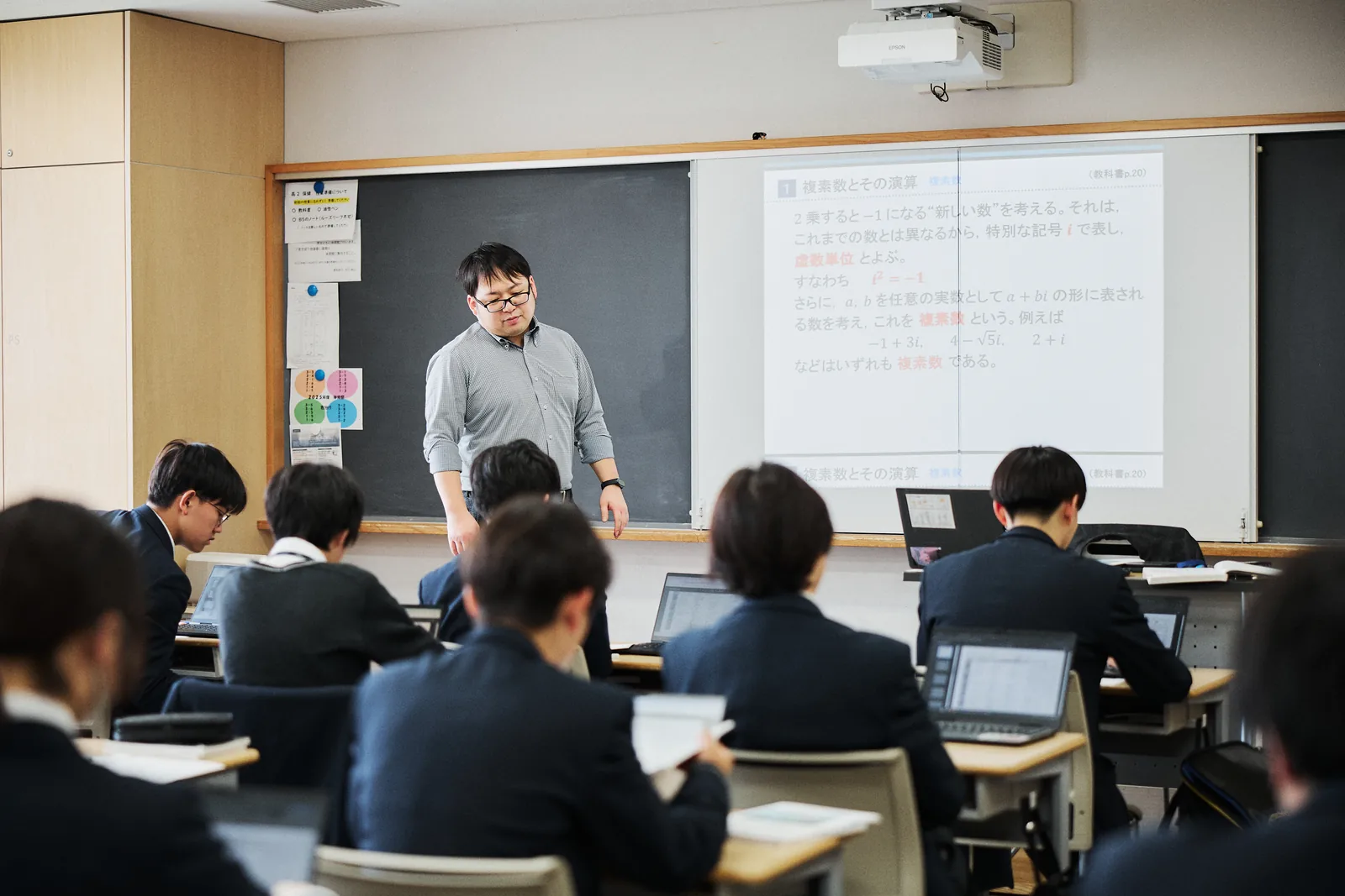 文教大学付属中学校・高等学校の授業の様子。前方の電子黒板に教材が映し出され、生徒がタブレットPCを開いている
