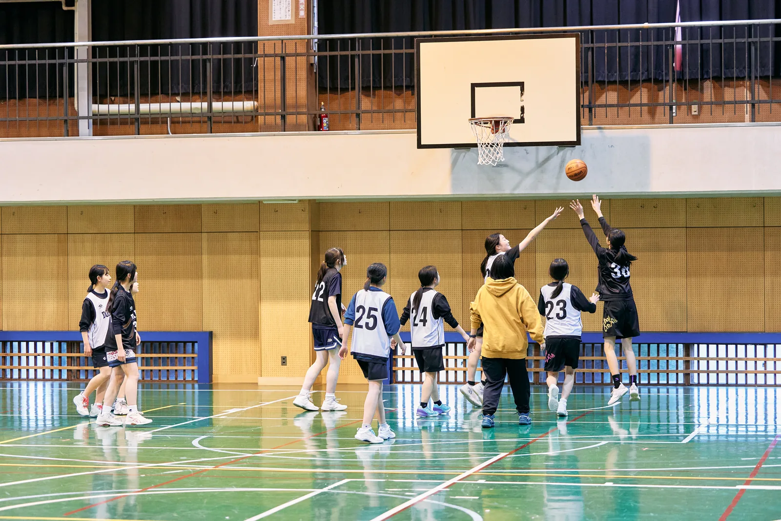 獨協埼玉中学高等学校の体育館。バスケットボールのシュートを放つ生徒と、コート上の生徒たち