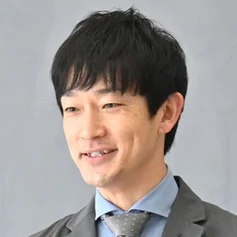 獨協埼玉中学高等学校の先生。教室で本を開いて生徒に話しているところ
