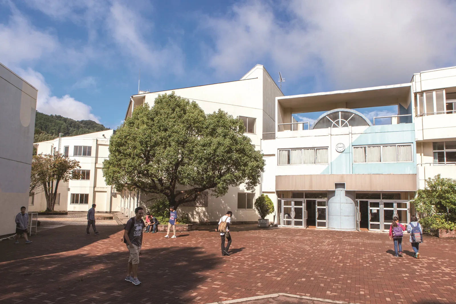 自由の森学園の校舎と中庭。れんが敷きの広場を生徒たちが歩いている