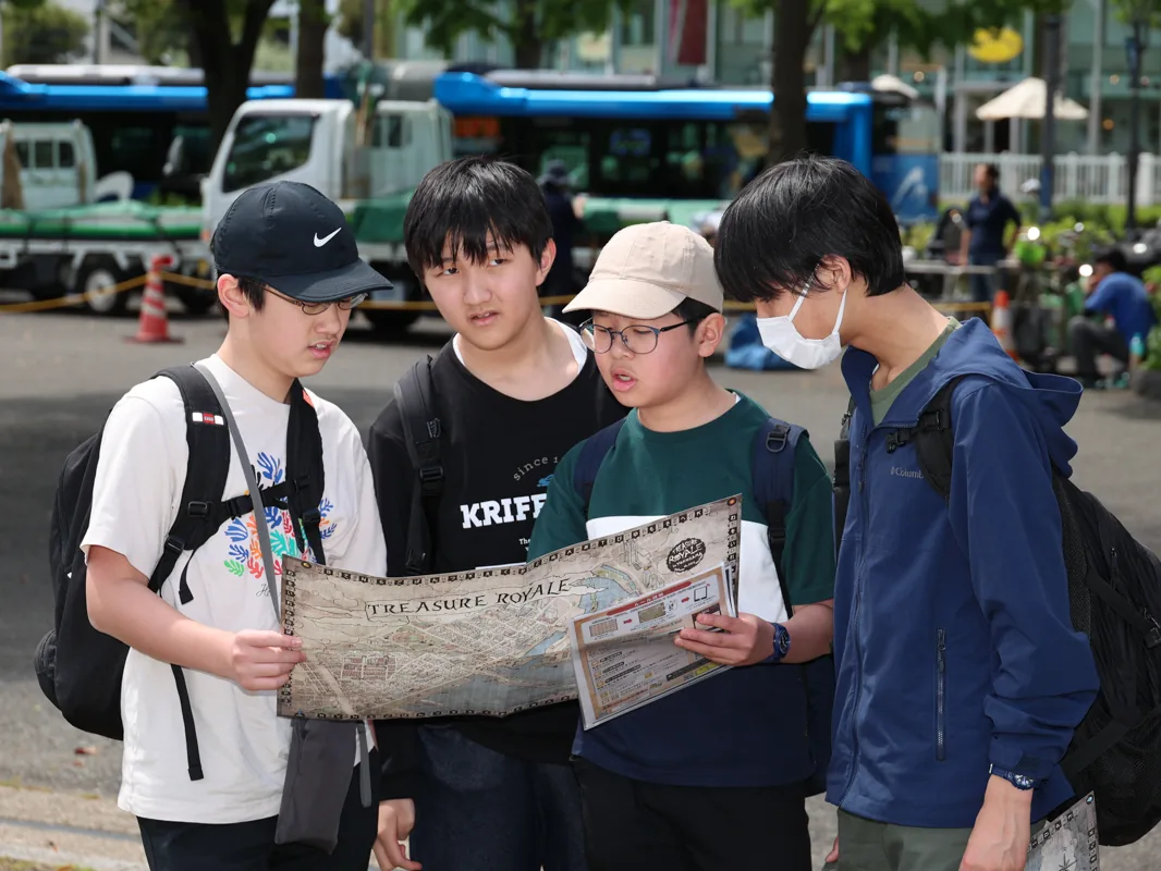 東京都市大学付属中学校・高等学校の校外学習。生徒たちが屋外で地図を広げて見ている